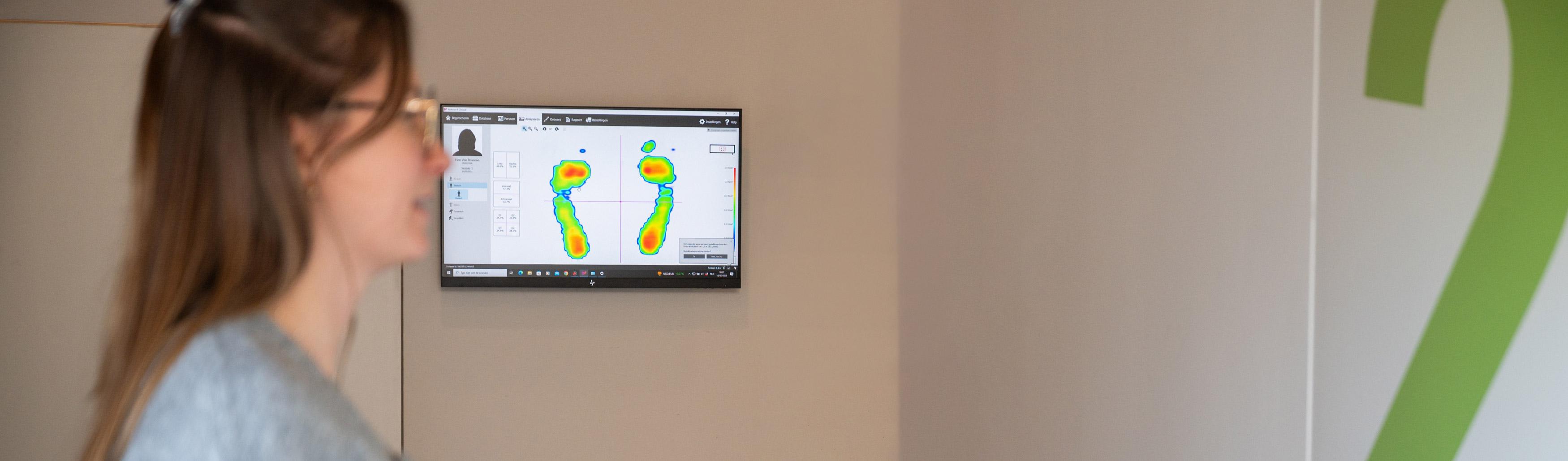 Patiente examinant les résultats d\'un examen podologique et d\'une cartographie des pressions plantaires sur écran.